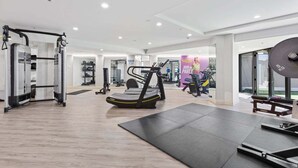 A gym with cardio equipment, weight machines, and a mirrored wall. - Stunning Views of Rangitoto Kitchen Gym Rooftop Pool Parking (Auckland)