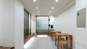 Un pasillo con una mesa y sillas de madera, una lavadora y un inodoro a la vista.