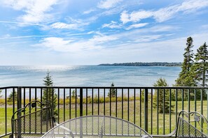 A balcony with a view of a lake and distant trees.