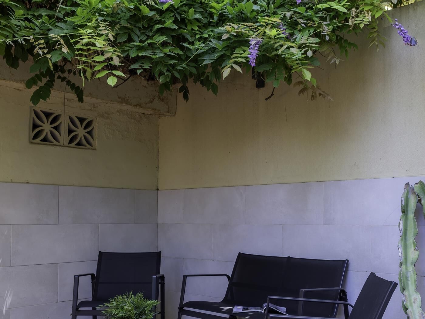 Un rincón amoblado con dos sillones, una pared texturizada y un ventanal con celosía decorativa.