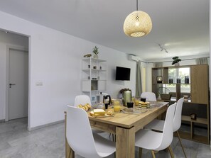 Un comedor moderno con una mesa de madera, sillas blancas y una lámpara colgante.