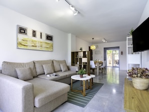 A modern living room with a sofa, a coffee table, and a dining area with chairs.