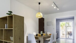 A modern dining area with a wooden table, chairs, and a pendant light. - Sunstay Carlota Flat II Torremolinos (Torremolinos)