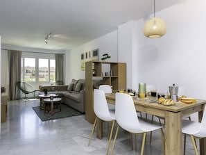 Un salon moderne comprenant un coin repas, un canapé, une table basse et une bibliothèque.