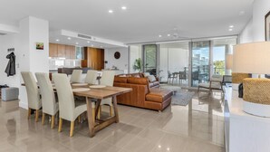 A modern living room with a dining area, a kitchen, and a balcony with outdoor seating.