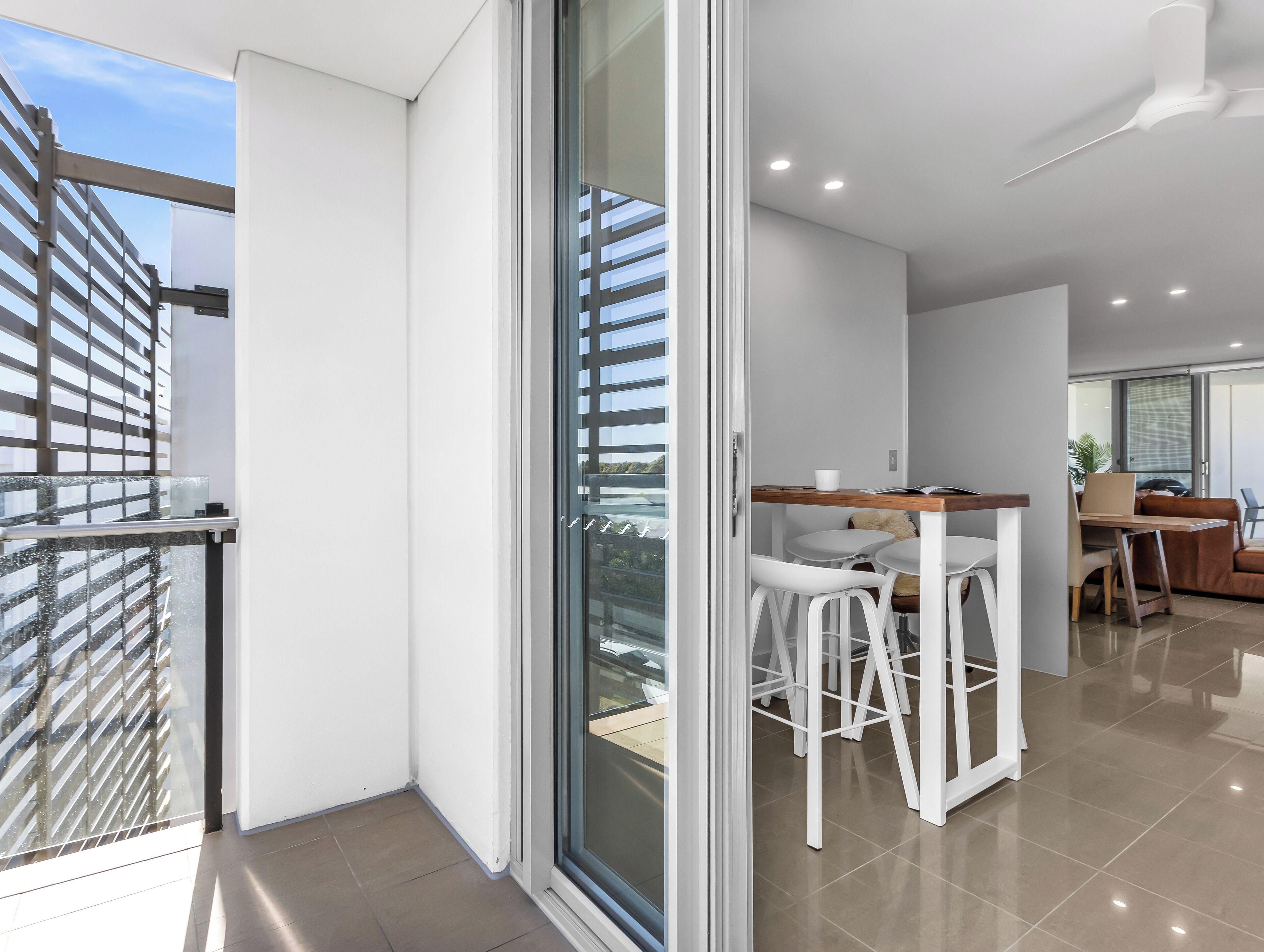 A modern apartment with a balcony, a dining area, and a kitchen.