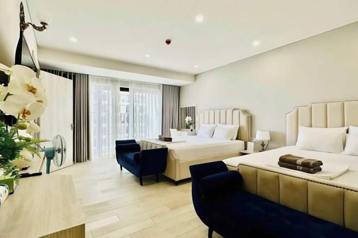 Habitación de hotel con dos camas, un escritorio, una silla y un ventanal grande.