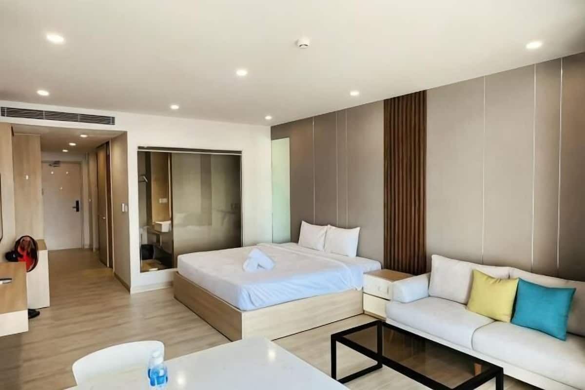 Una habitación de hotel moderna con cama, sofá y una pequeña mesa.