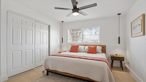 A bedroom with a bed, a ceiling fan, a window with blinds, a nightstand, and a framed picture on the wall. - 3BR Home • River Access • Boating • Screened Lanai (Fort Myers)