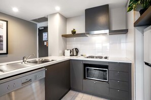 A modern kitchen with a dishwasher, stove, microwave, and a small oven.