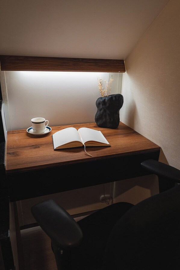 A wooden desk with a cup, saucer, and a book under a light. - Charming 3-bedroom apartment with rooftop pool in Barranco (Barranco)