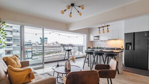 A modern apartment with a living area, kitchen, and large windows offering city views. - Charming 3-bedroom apartment with rooftop pool in Barranco (Barranco)