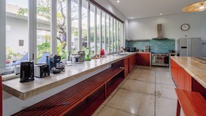 A modern kitchen with a long counter, built-in appliances, and large windows. - Jimbaran Beach Bliss Villa Bali (Kedonganan)