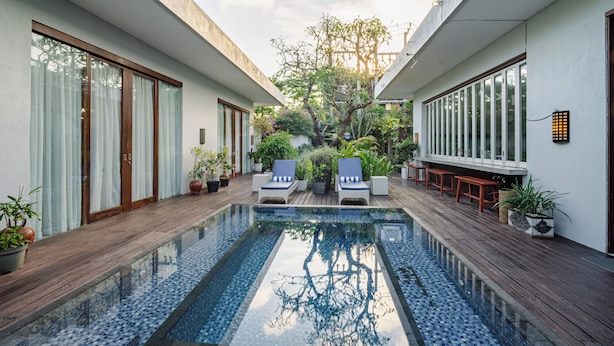 A modern pool area with a wooden deck, lounge chairs, and potted plants. - Jimbaran Beach Bliss Villa Bali (Kedonganan)