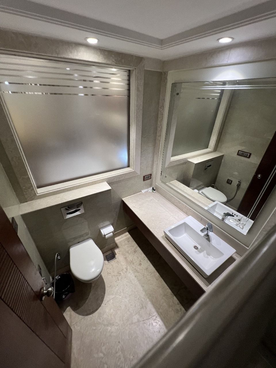 A modern bathroom with a toilet, sink, and large mirror.