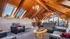 Et rummeligt loft med højt til loftet, træbjælker og store vinduer.