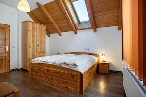 Un dormitorio con cama de madera, tragaluz, mesita de noche y armario.