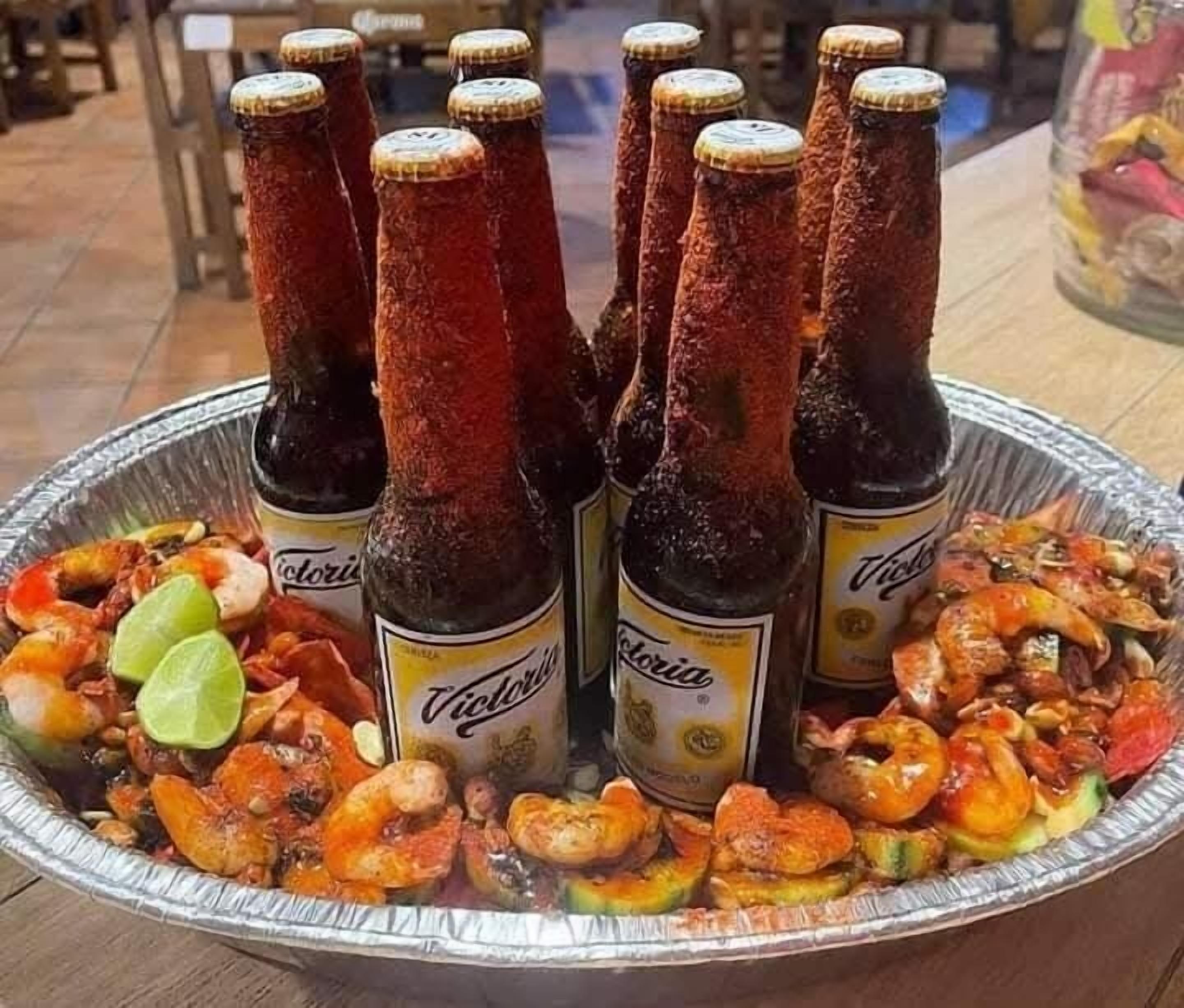A tray with several bottles of Victoria beer and a variety of seafood, including shrimp and crab legs.