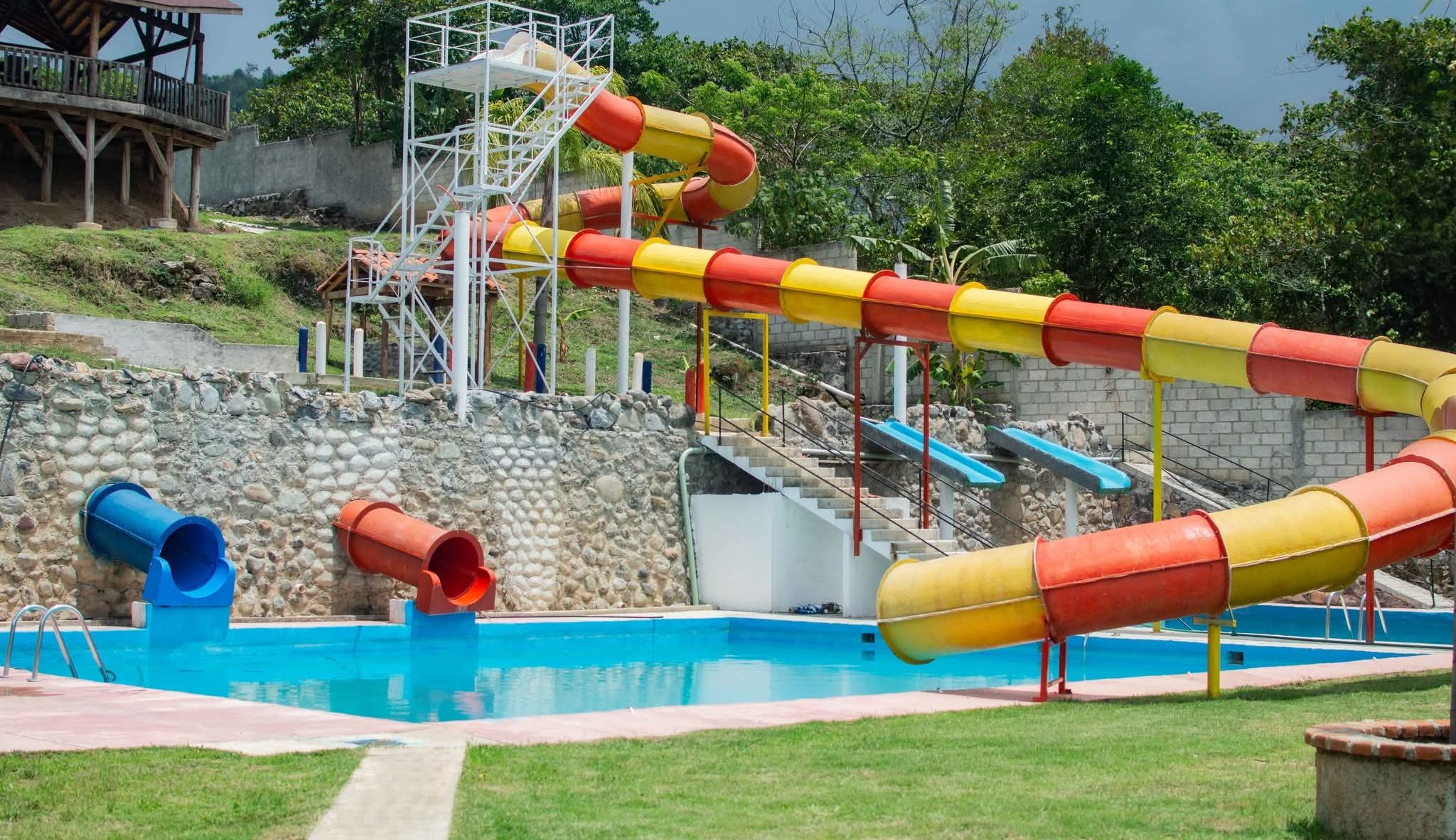 A water park with a pool, slides, and a wooden structure.