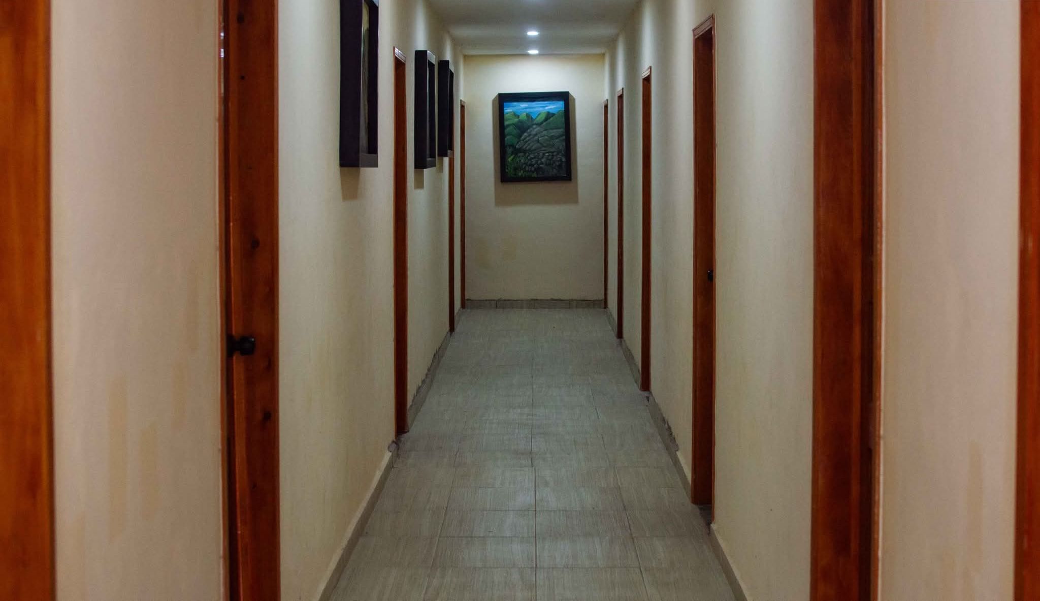 A hallway with wooden doors on both sides, a tiled floor, and a framed picture on the wall.