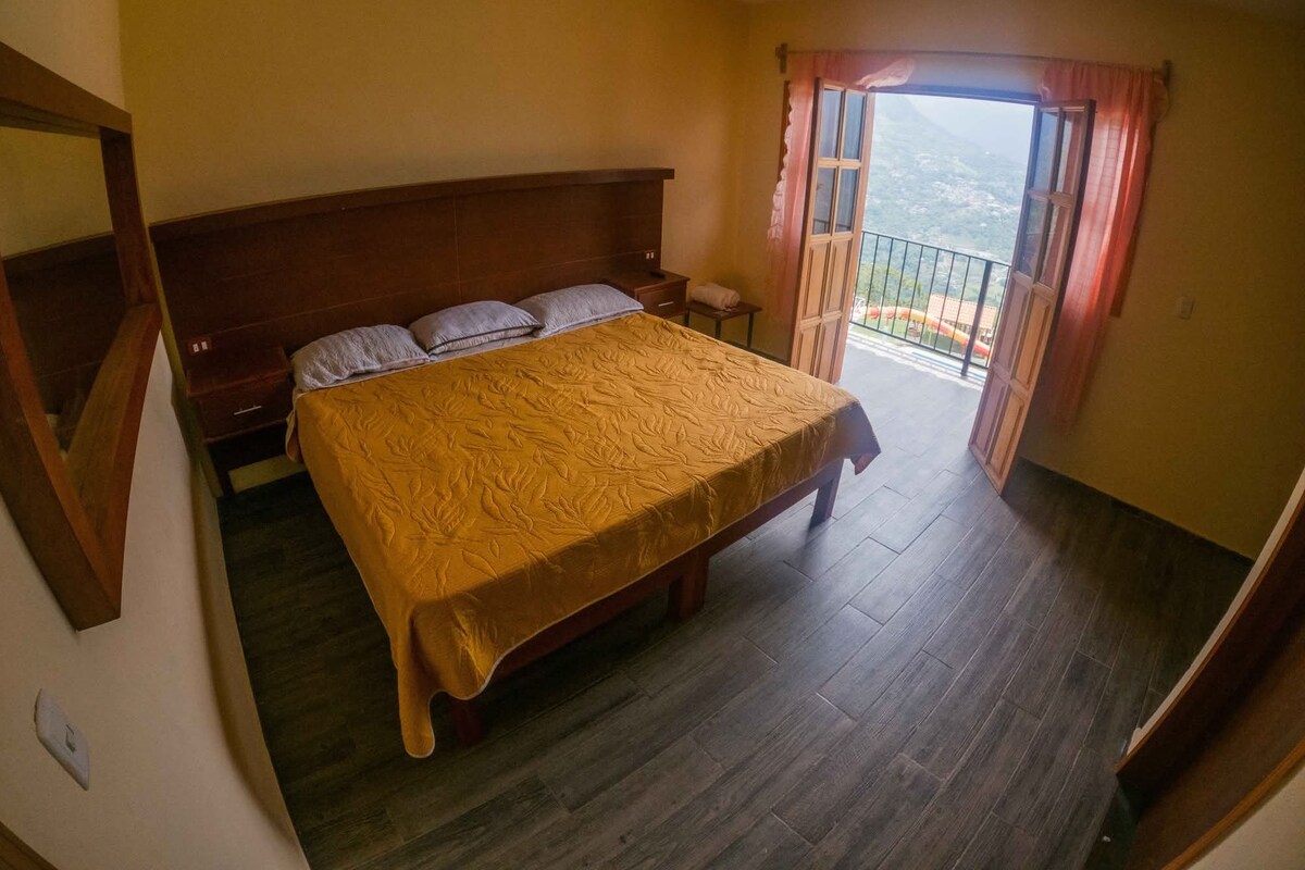 Un dormitorio con una cama grande, cabecera de madera y un balcón con vistas.
