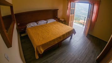 Un dormitorio con una cama grande, cabecera de madera y un balcón con vistas.