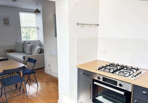 Una cocina compacta con estufa a gas, horno y comedor con mesa y sillas.