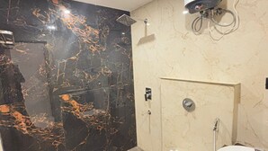 Une salle de bain avec un mur en marbre noir, une douche, des toilettes et un lavabo.