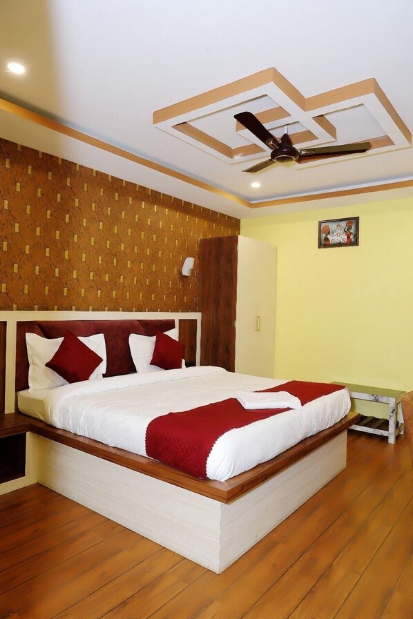A bedroom with a large bed, wooden headboard, and a ceiling fan.