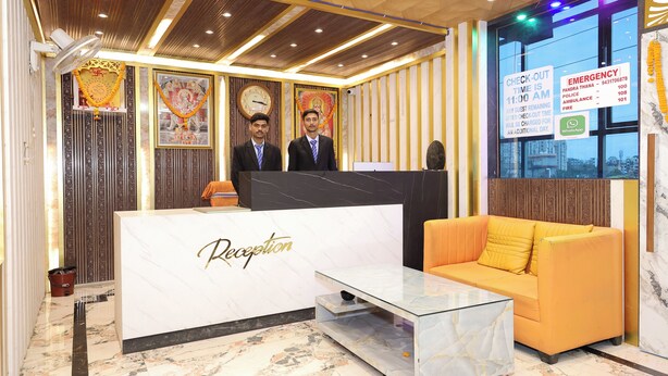 A reception area with a marble reception desk, a glass coffee table, and an orange sofa. - Hotel Shree Mani Residency (Ranchi)