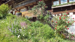 A traditional wooden building with balconies, surrounded by lush greenery and various flowering plants. - Apartment 'Talblick' with Shared Terrace, Garden, and Wi-Fi (Gengenbach)