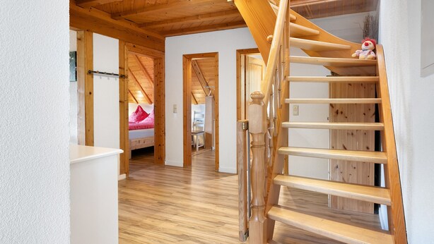 A wooden staircase leading to a bedroom with a bed and a small toy on the bed. - Apartment 'Talblick' with Shared Terrace, Garden, and Wi-Fi (Gengenbach)
