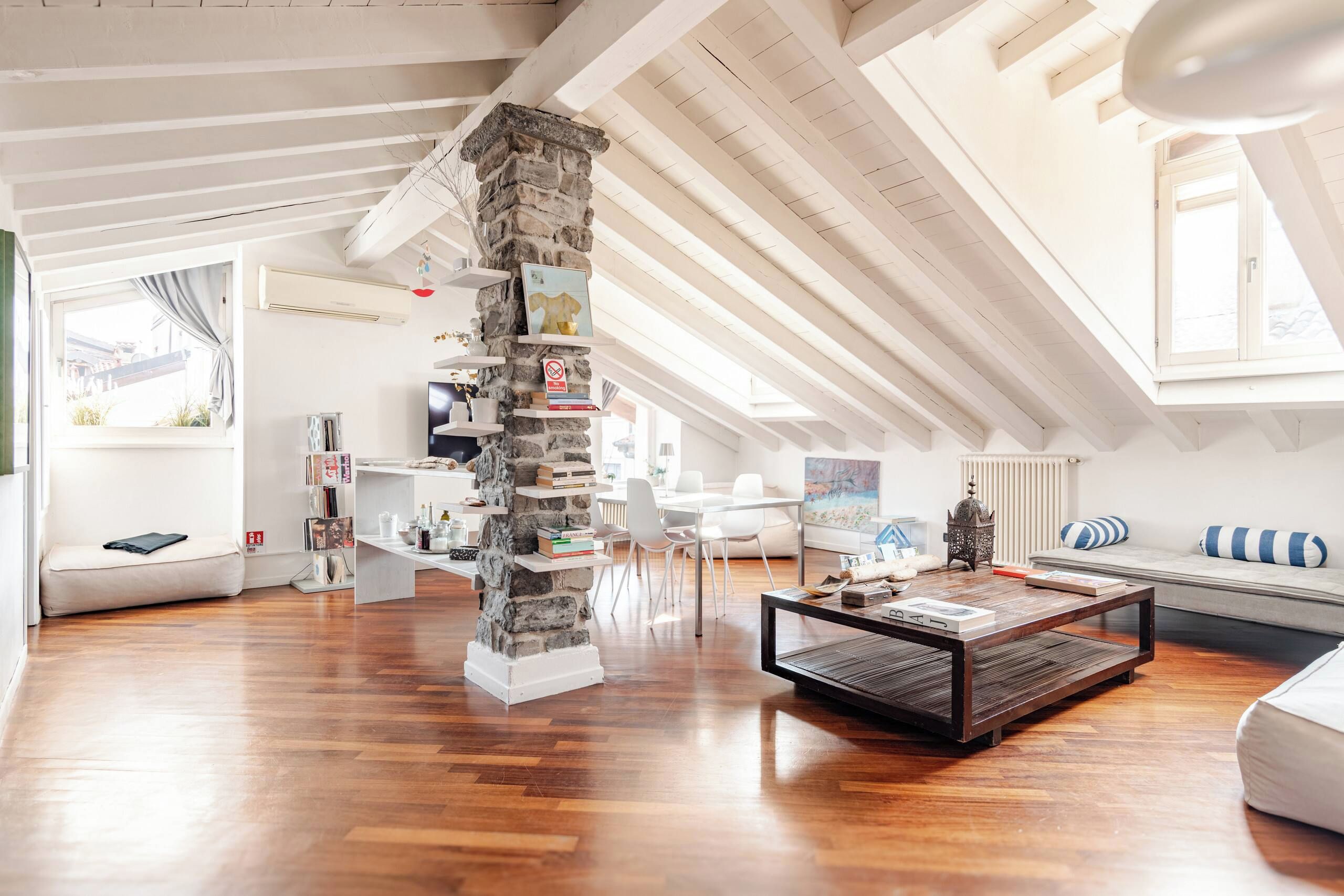 Ein geräumiges Loft mit hohen Decken, freiliegenden Balken und einer Steinsäule.