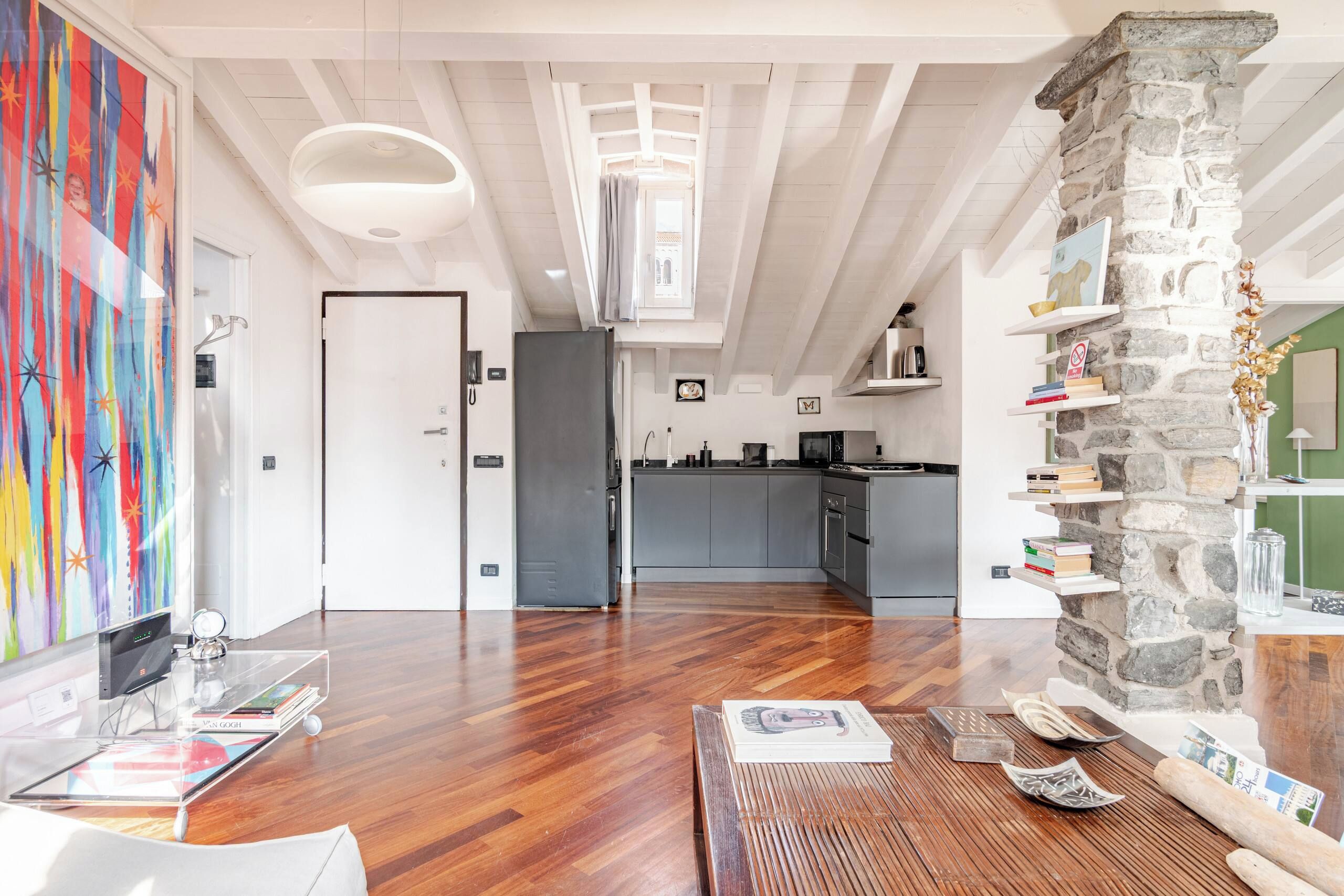 Un interno moderno con cucina, zona pranzo e soggiorno con un quadro di grandi dimensioni.