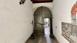 A corridor with a stone floor, wooden ceiling beams, and a large arched doorway. - Vanessa's Art Rooftop (Como)