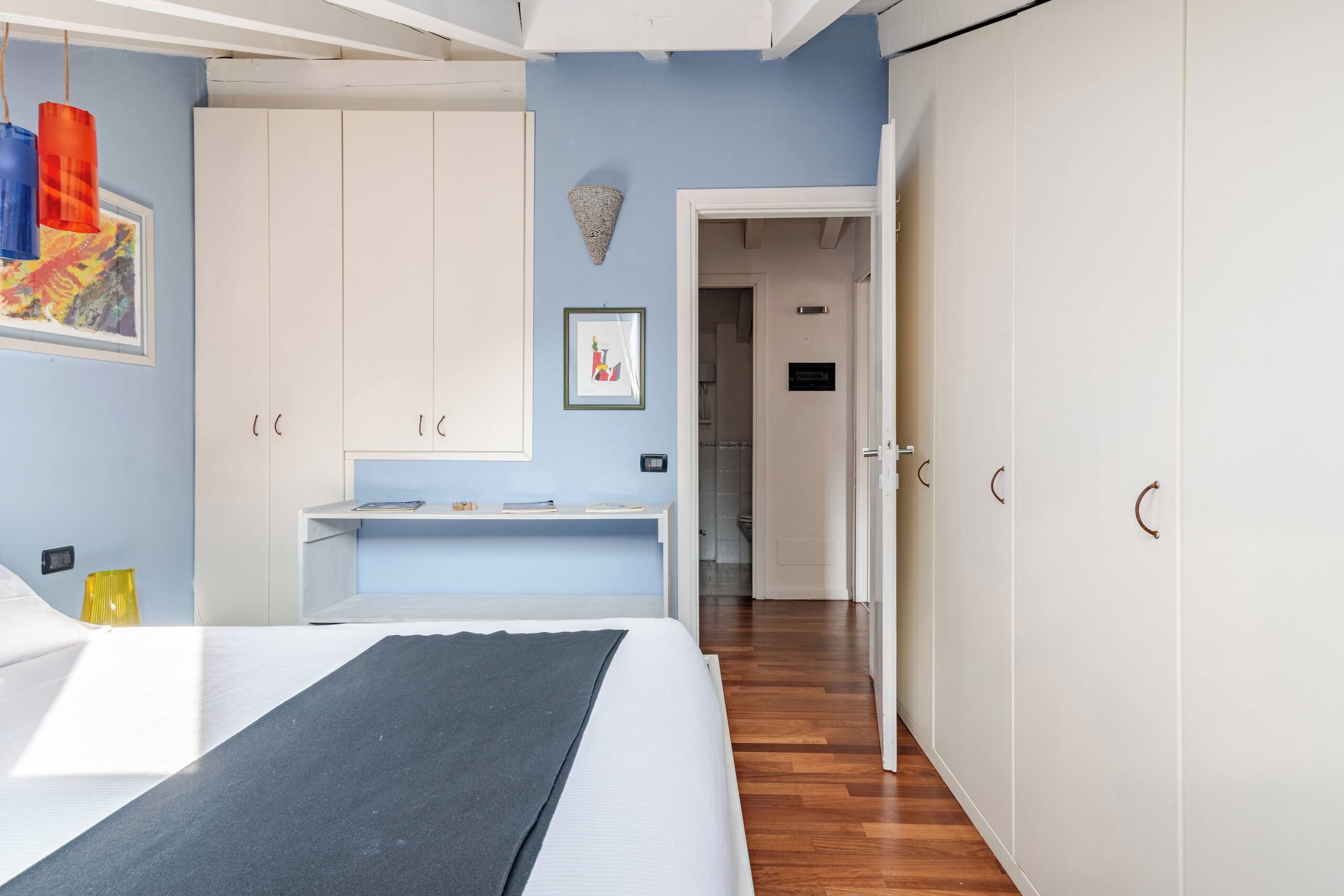 A bedroom with a bed, a desk, and a wardrobe.