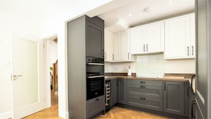 A modern kitchen with grey cabinets, a built-in oven, and a wooden herringbone floor. - 3 Bed Home W/Garden By Phoenix Park & Dublin Zoo (Sublin 7)