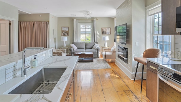 A modern kitchen with a marble countertop, wooden flooring, and a built-in oven. - Historical Housatonic Street apartment (Lenox)