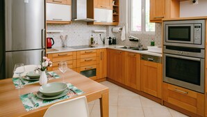 A modern kitchen with wooden cabinets, stainless steel appliances, and a dining area set for two.