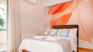 A hotel room with a bed, white curtains, a radiator, a wall-mounted air conditioner, and a window.