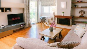 A modern living room with a flat-screen TV displaying 'NETFLIX', a sofa, a coffee table, and a fireplace.
