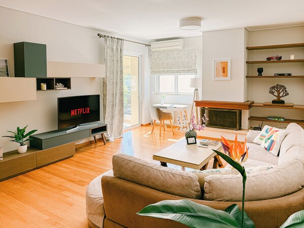 A modern living room with a flat-screen TV, a sofa, a coffee table, and a fireplace.
