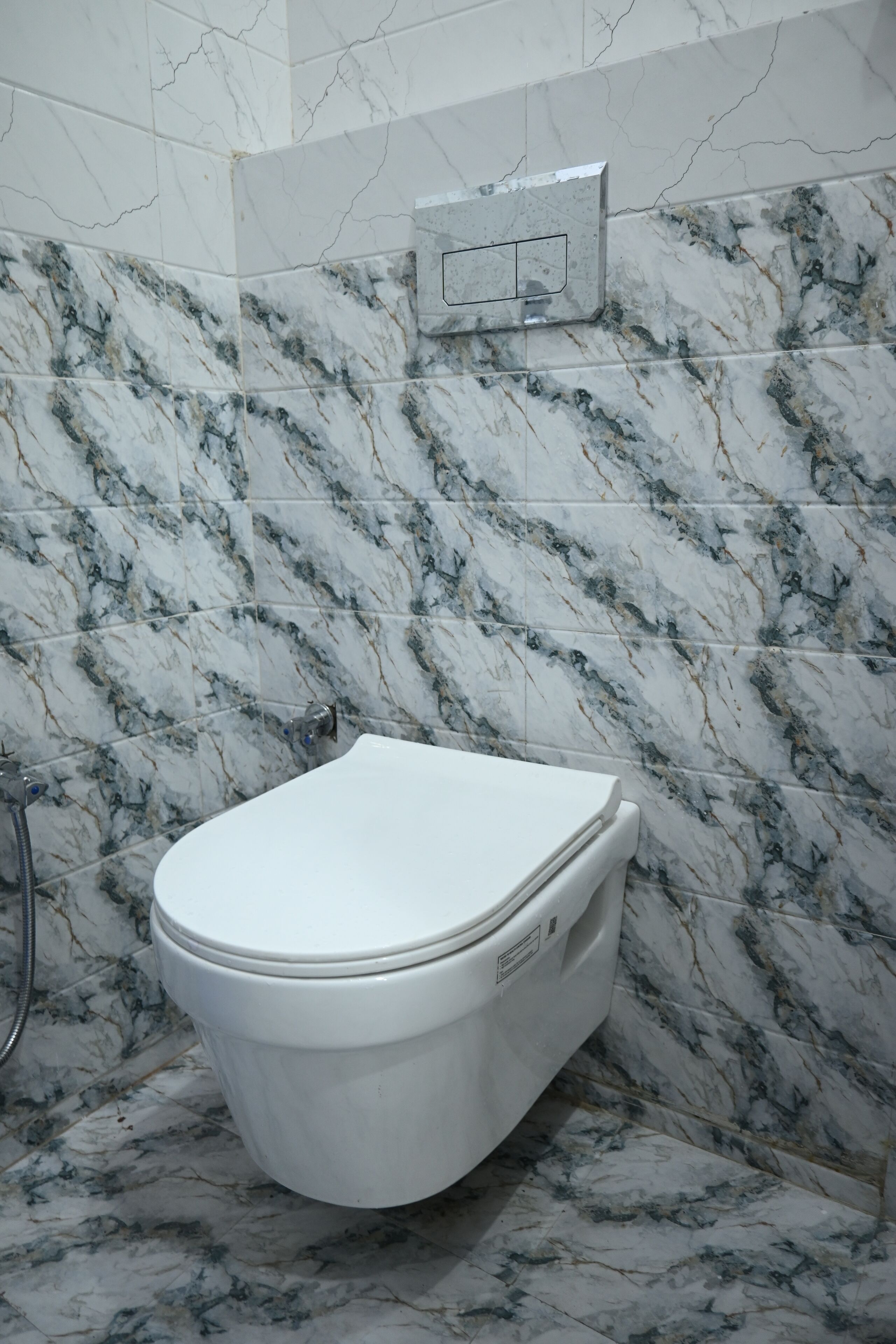 Un bagno con il water, pareti a effetto marmo e una doccia.
