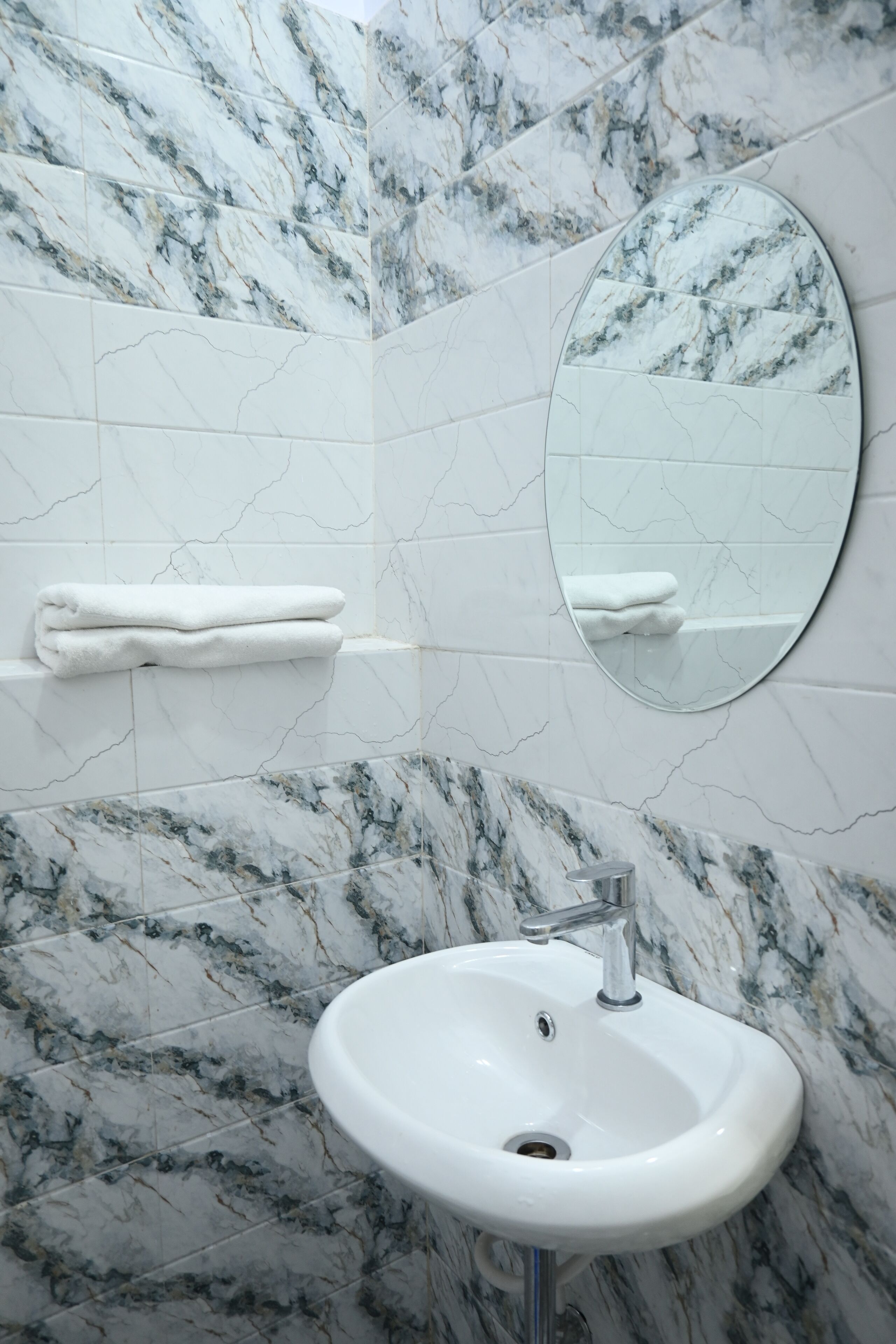 A bathroom with a white sink, a mirror, and a towel rack.