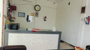 A reception area with a desk, chairs, a clock, and a fire extinguisher.