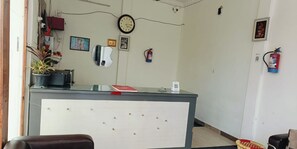 A reception area with a desk, chairs, a clock, and a fire extinguisher. - Hotel T Star (Meerut)