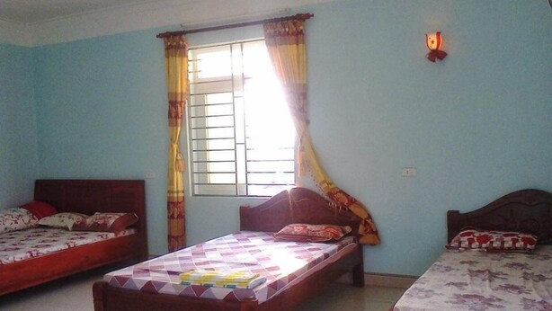 Une chambre avec deux lits simples, une fenêtre avec des rideaux et un luminaire fixé au mur.