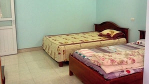 Une chambre avec deux lits, une porte et un interrupteur sur le mur.