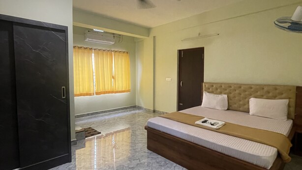 Un dormitorio con cama, ventilador de techo, aire acondicionado y una puerta.