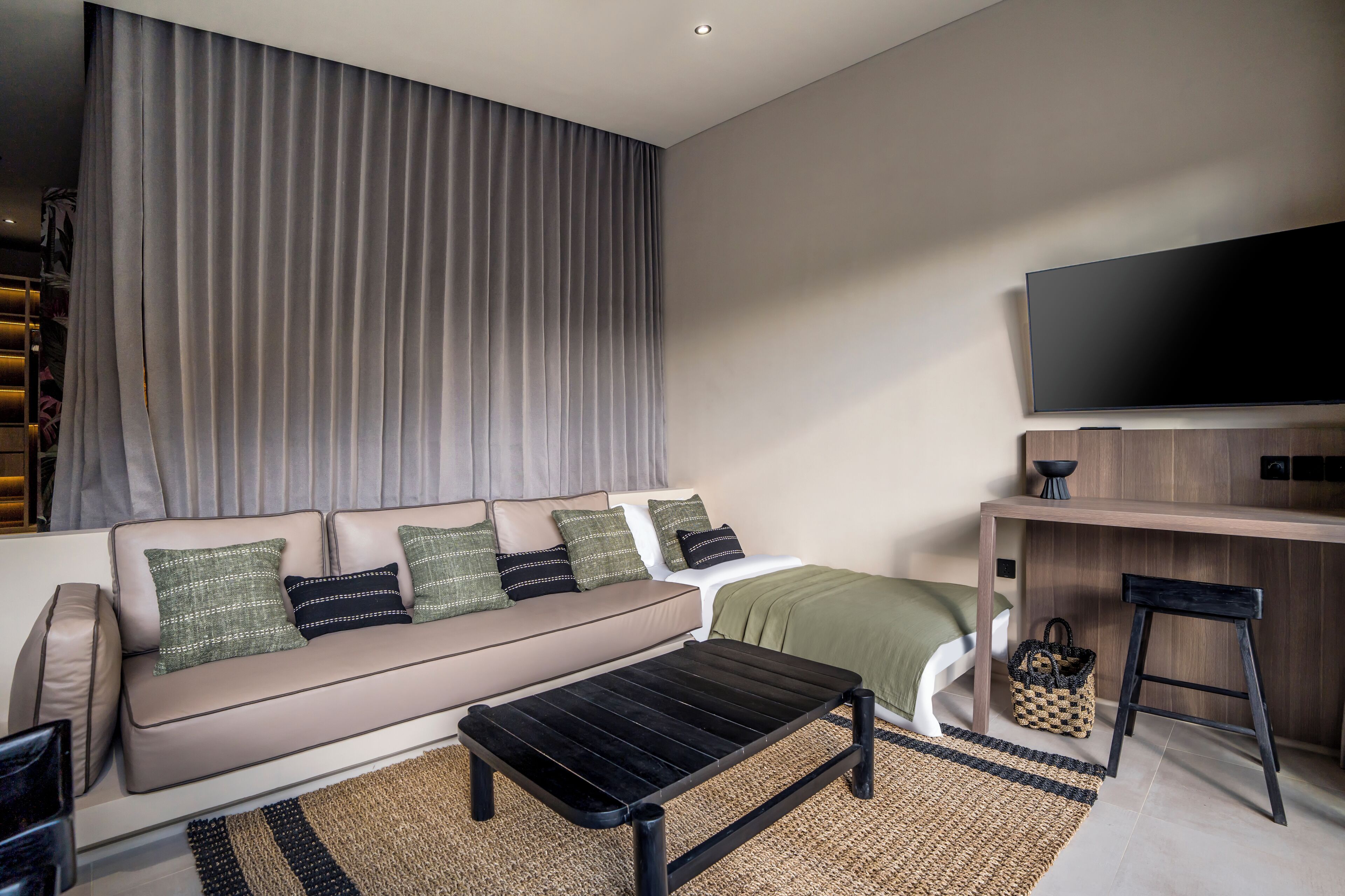 A modern living room with a sofa, coffee table, and a TV mounted on the wall.